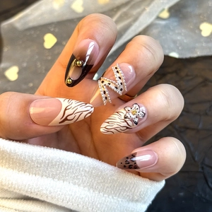 Detail of almond-shaped press-on nails with leopard print, 3D gold beads and silver chain