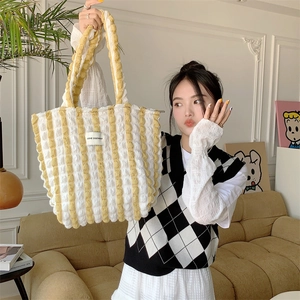 Detail of yellow and white striped tote bag showing bubble texture fabric and brand label