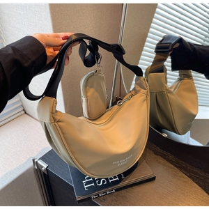 Dettaglio della borsa a mezzaluna in nylon albicocca con tracolla e piccolo astuccio zip