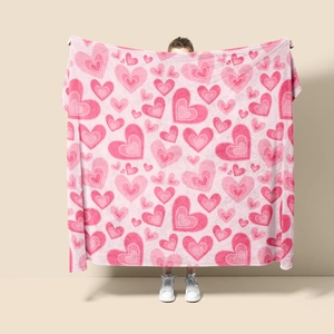 Detail of pink flannel blanket featuring heart patterns held by model on plain background
