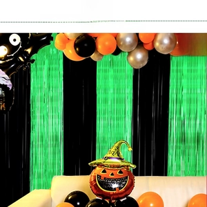 Macro shot of Halloween decor with black and green tinsel foil curtains and pumpkin balloon