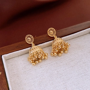 Macro detail of 14K gold plated Jhumka earrings with hollow flower studs and bead tassels