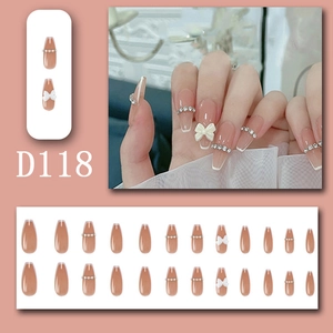 Nude pink French press-on nails with white bow and rhinestone chain detailing