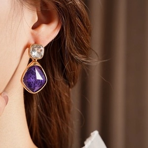Gros plan de boucles d'oreilles vintage en or avec cristaux violets sur un mannequin