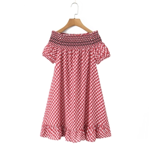 Détail d'une robe vichy rouge à épaules dénudées avec broderie noire sur l'encolure