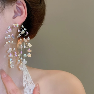 Close-up of colorful beaded fringe earrings on a model with dangling sequins and studs