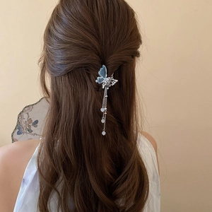 Détail d'une pince à cheveux papillon bleu avec glands métalliques et perles