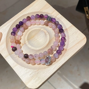 Detailed macro view of amethyst and quartz beaded bracelets in a wooden tray