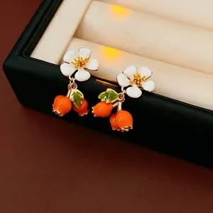 Vintage floral drop earrings with white petals and orange berry charms on a gift box