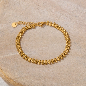Detail of gold wheat leaf chain bracelet with lobster clasp on natural stone background