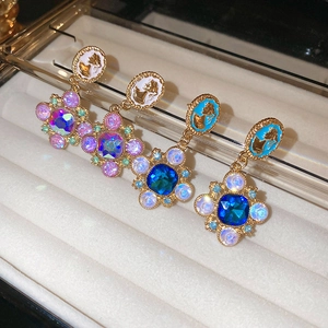 Détail de boucles d'oreilles vintage en résine gaufrée et gemmes dans un écrin