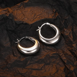 Top-down view of polished silver U-shaped hoop earrings on dark textured background