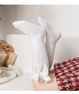 Détail de chaussettes hautes blanches en coton peigné pour filles avec un grand nœud doré