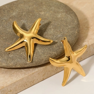 Polished gold starfish stud earrings displayed on natural beach stones in ocean style