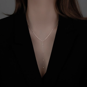 Minimalist silver geometric Y-shaped tassel necklace on model with elegant drop beads