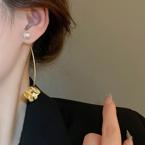 Close-up of elegant gold flower earrings with white pearls worn on a female model