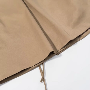 Detail view of the khaki trench coat hem featuring functional adjustable drawstrings