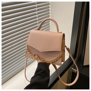 Pink PU leather crossbody bag with chain and croc texture by white shutter window