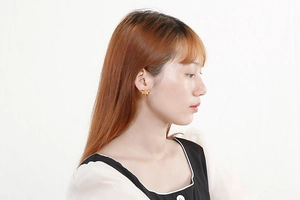 Detail shot of a model wearing minimalist golden dragonfly stud earrings in stainless steel