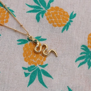 Elegant gold snake pendant necklace with diamonds and green gemstone eyes for women