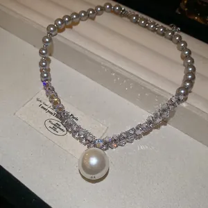 Elegant necklace with grey pearls, sparkling crystals, and a large central pearl pendant