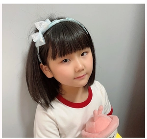 Detail of light blue polka dot bow headband with pearl accents on a young girl