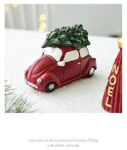 Voiture de Noël miniature en résine rouge portant un sapin sur neige avec effet bokeh