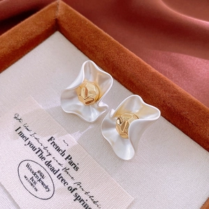 Detailed macro view of French style wavy petal earrings on red velvet with gold center