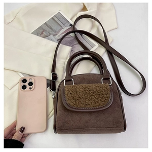 Detailed view of plush brown suede handbag with faux shearling trim and silver hardware