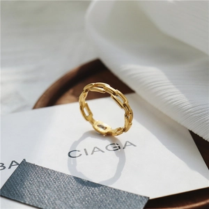 Gros plan détaillé de la bague chaîne en or 18 carats sur un tissu texturé blanc