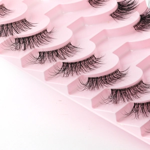 Close-up of black voluminous false eyelashes arranged in a pink wavy display tray