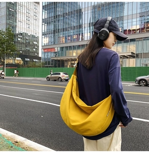 Street view of a large yellow Oxford cloth crossbody bag with a casual crescent shape