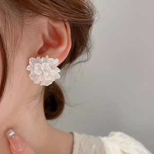 Elegant white acrylic flower stud earrings worn by a model for a stylish daily look