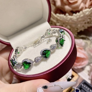 Detailed view of silver bracelet with green heart gemstone in a red jewelry box