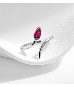 Macro shot of silver snake ring with a teardrop red gemstone on white surface