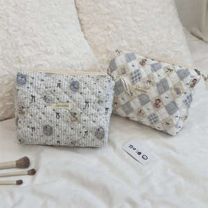 Détail des trousses de maquillage en coton matelassé avec motifs d'ours et fermeture