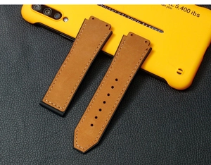 Detail showing brown leather watch strap with white stitching and black rubber back