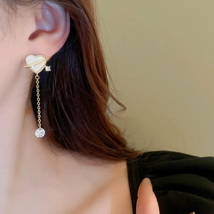 Macro shot of gold heart tassel earrings with planet ring design and zircon drops