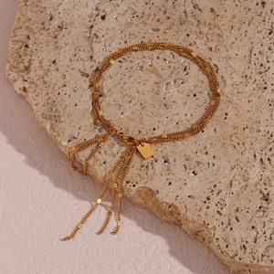 Close-up of golden multi-layer tassel bracelet with circular sequins on stone background