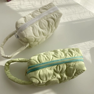 Detailed close-up of quilted floral makeup bags in cream and green with blue zipper