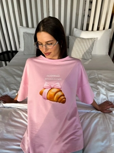 Λεπτομέρεια ροζ βαμβακερού t-shirt με τύπωμα κρουασάν και μεταξωτό φιόγκο στο στήθος