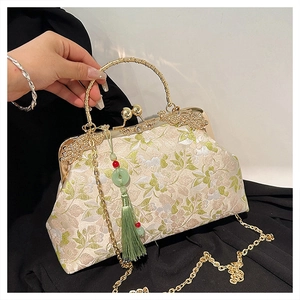 Detail of embroidered floral handbag with gold metal handle and green silk tassel
