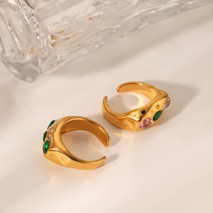 Detail of two gold irregular hammered rings featuring colorful inlaid zircon stones