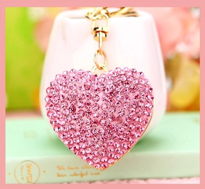 Macro detail of heart keychain with pink rhinestones and gold metal chain link