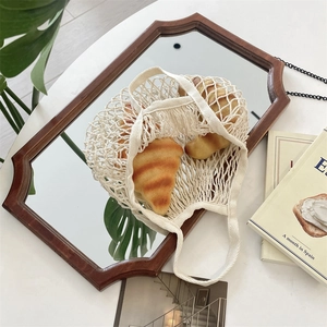 Vue détaillée du sac filet tissé crème avec un motif évidé artisanal élégant
