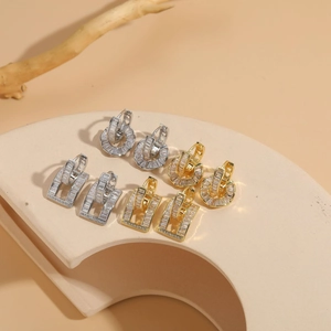 Detailed display of zircon hoop earrings in gold and silver finishes on stone pedestal