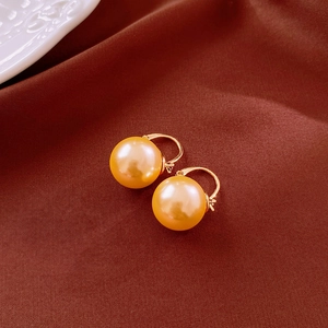 Macro de boucles d'oreilles créoles perles dorées sur un fond de soie élégant