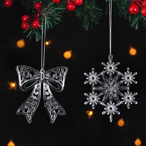 Clear acrylic bow and snowflake Christmas ornaments with silver strings on a dark background