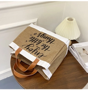 Detailed close-up of jute tote bag with enjoy the little things print and leather handles