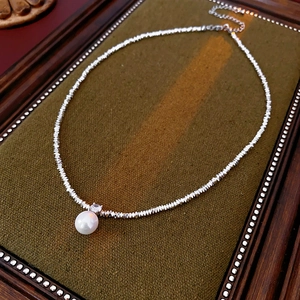 Detailed view of silver bead necklace with a white pearl pendant and zircon inlay